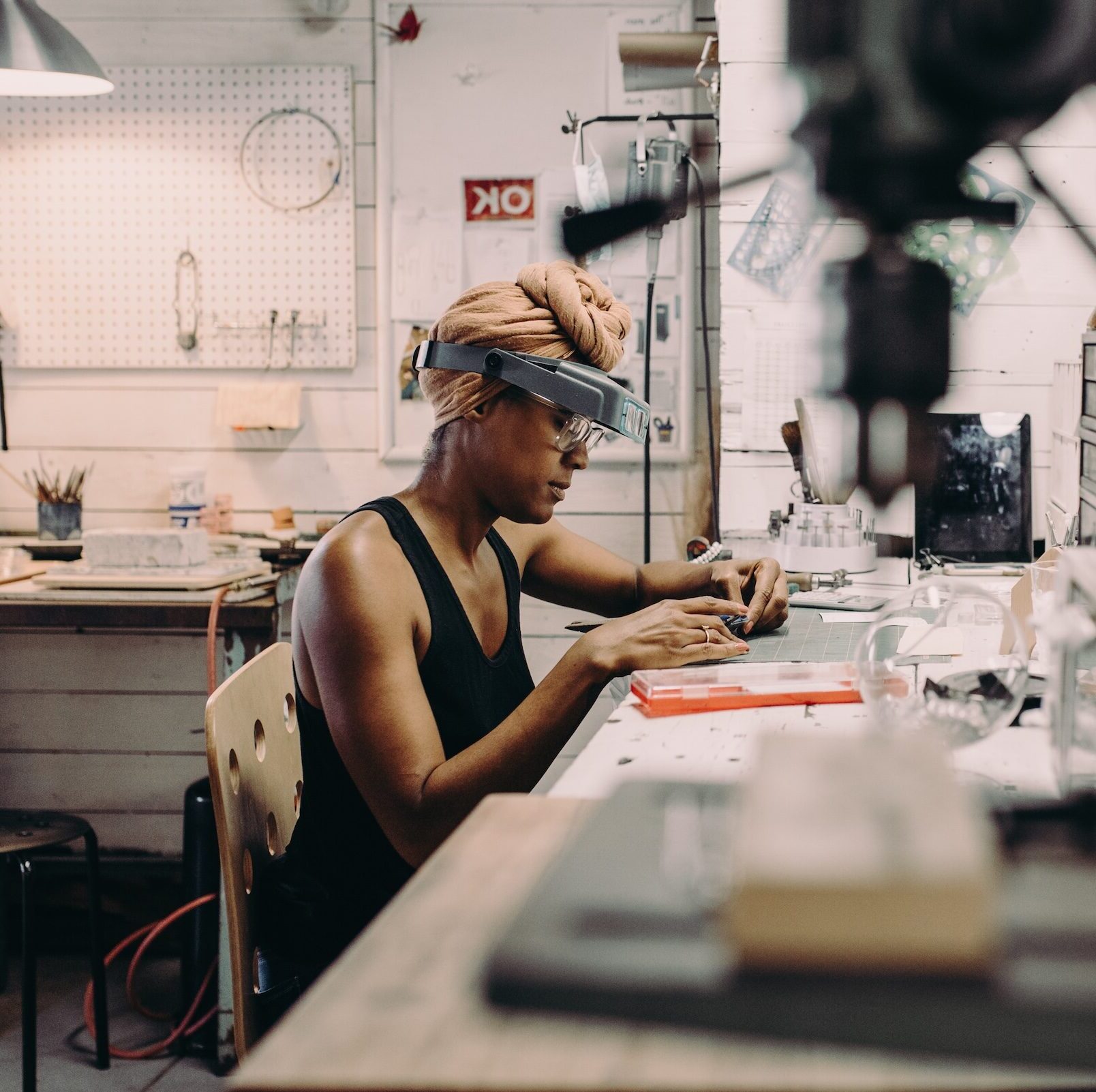 A young dark-skinned woman crafting jewellery at a workbench